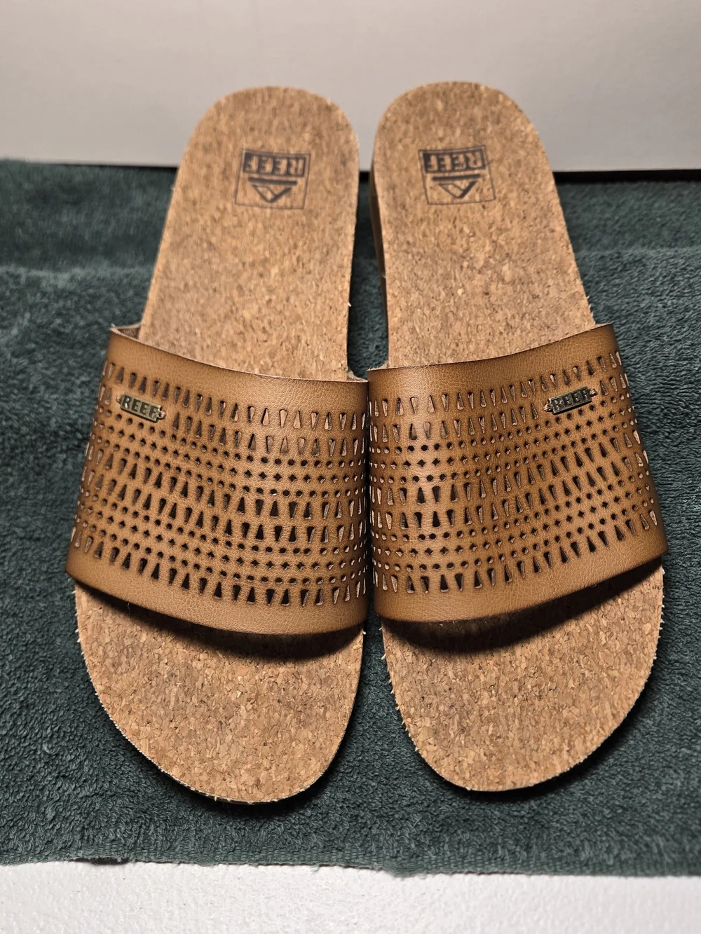 Reef women's comfort slide sandals featuring a soft cork footbed and perforated